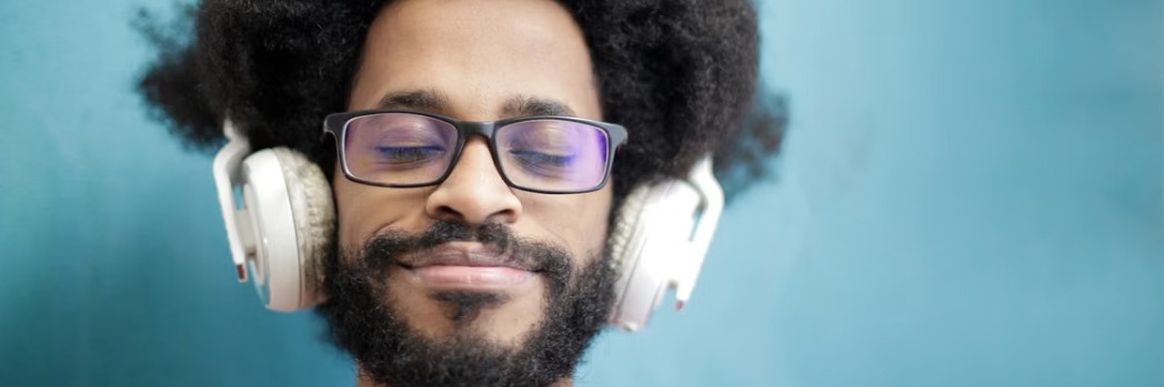 Homem sorridente de olhos fechados a sentir a música com auscultadores